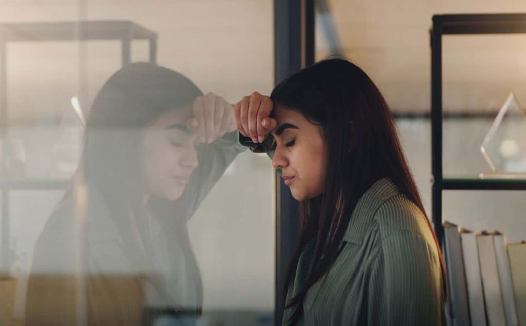 Female executive standing with tense posture looking stressed and overwhelmed.
