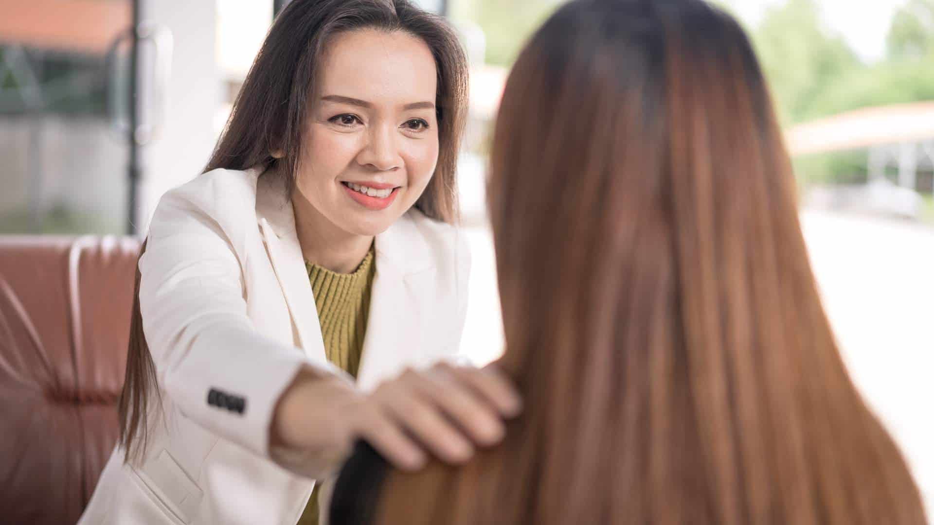 Close-up of a therapist's hand touching a woman's shoulder in comfort during a supportive session at a drug rehab near Atlantic City, NJ.