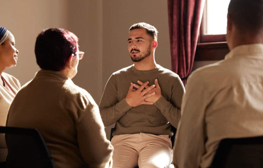 Man participating in a group counseling session asking, "Do I need rehab?